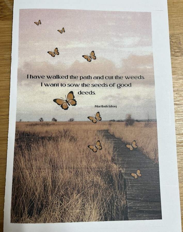 A paper program printed with a path through the grass and butterflies. Text reads "I have walked the path and cut the weeds. I want to sow the seeds of good deeds."