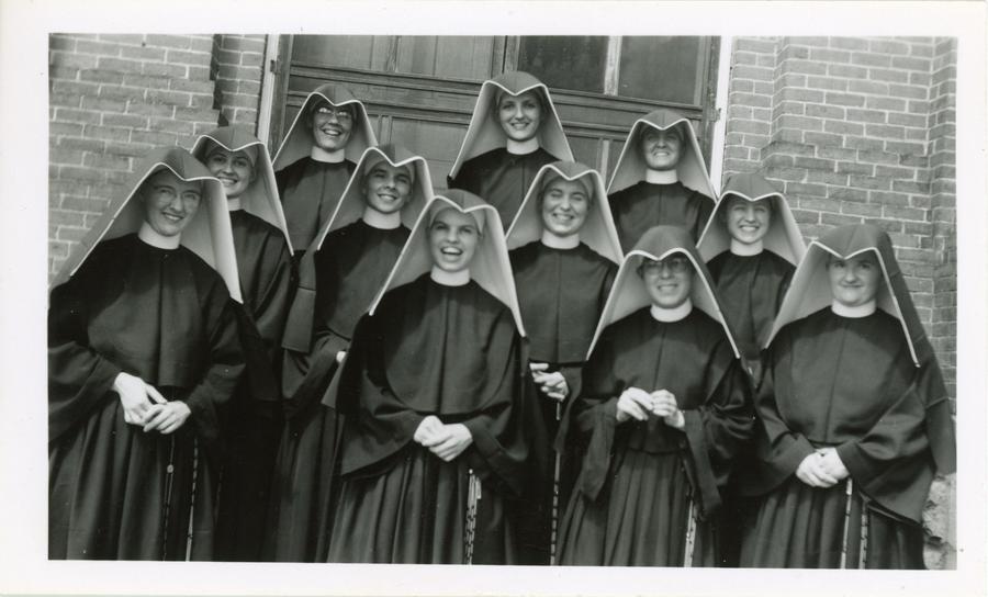 Archival photo of the 1944 Loretto Heights College reception class - eleven women in habits posing for a photo with joyous expressions on their faces.