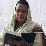 A Pakistani sister of Loretto is shown reading a bible passage wearing an intricately patterned outfit.