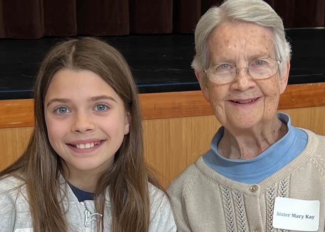 A photo of an elementary student with a religious sister smiling together.