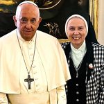 A photo of the Pope with a religious sister in habit standing next to him smiling.
