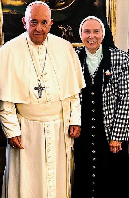 A photo of the Pope with a religious sister in habit standing next to him smiling.