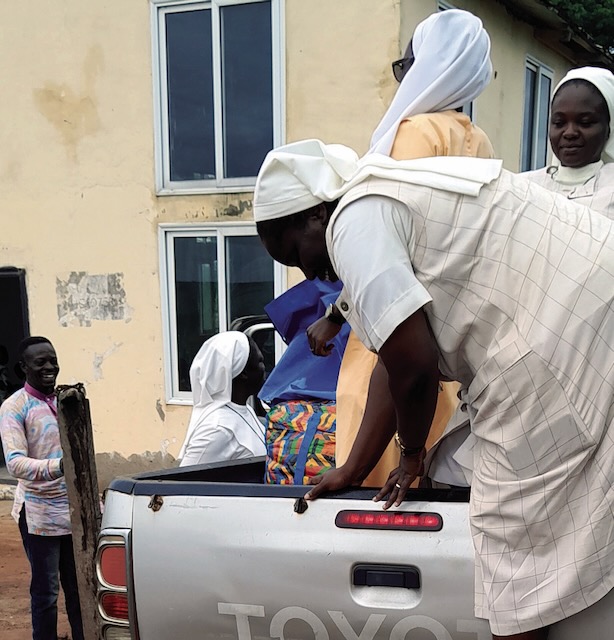 Ghanian religious sisters are shown packing up a silver Toyota truck bed with supplies in order to serve the rural poor in the area.