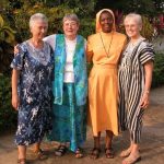 Four women in Ghanaian attire pose for a photo.