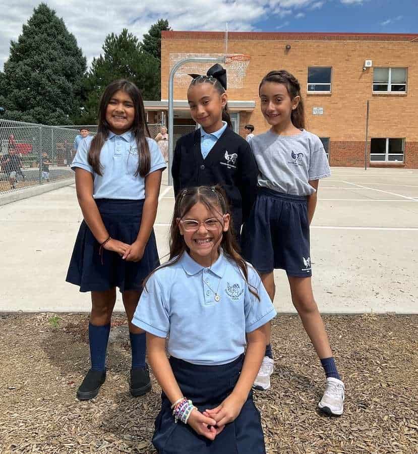 Four girls in school uniforms pose for a group picture during recess at Escuela de Guadalupe.