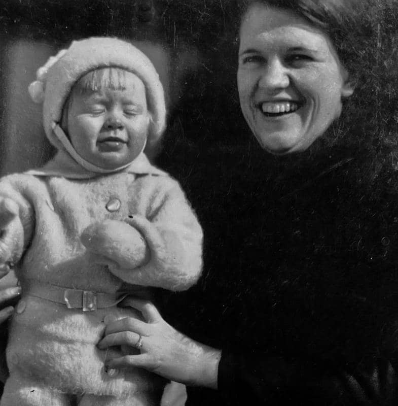 A black and white picture of a mother holding her baby smiling brightly for a picture.