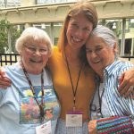 During a lunch break from a gathering, three women enjoy a hug and smile for the camera.