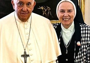 A photo of the Pope with a religious sister in habit standing next to him smiling.