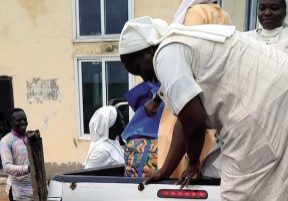 Ghanian religious sisters are shown packing up a silver Toyota truck bed with supplies in order to serve the rural poor in the area.